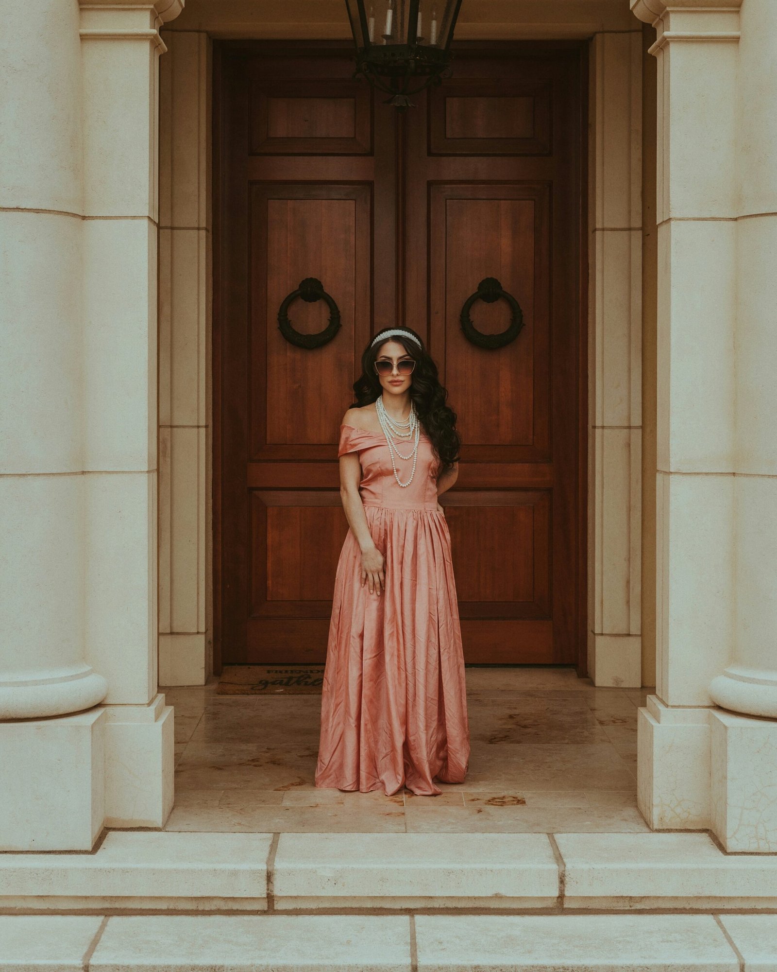 A woman in a pink dress standing in front of a door